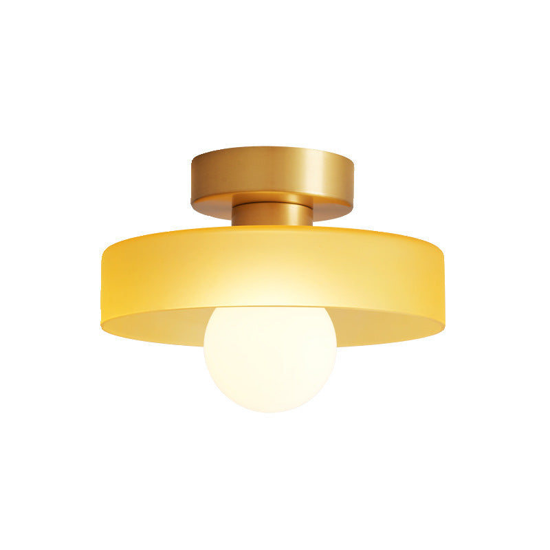 Ceiling light with round amber glass shade and gold metal top, glowing bulb