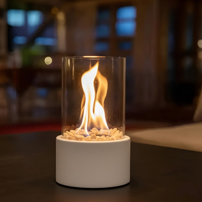 Tabletop bioethanol fireplace with clear glass fire bowl and white metal base, flames inside