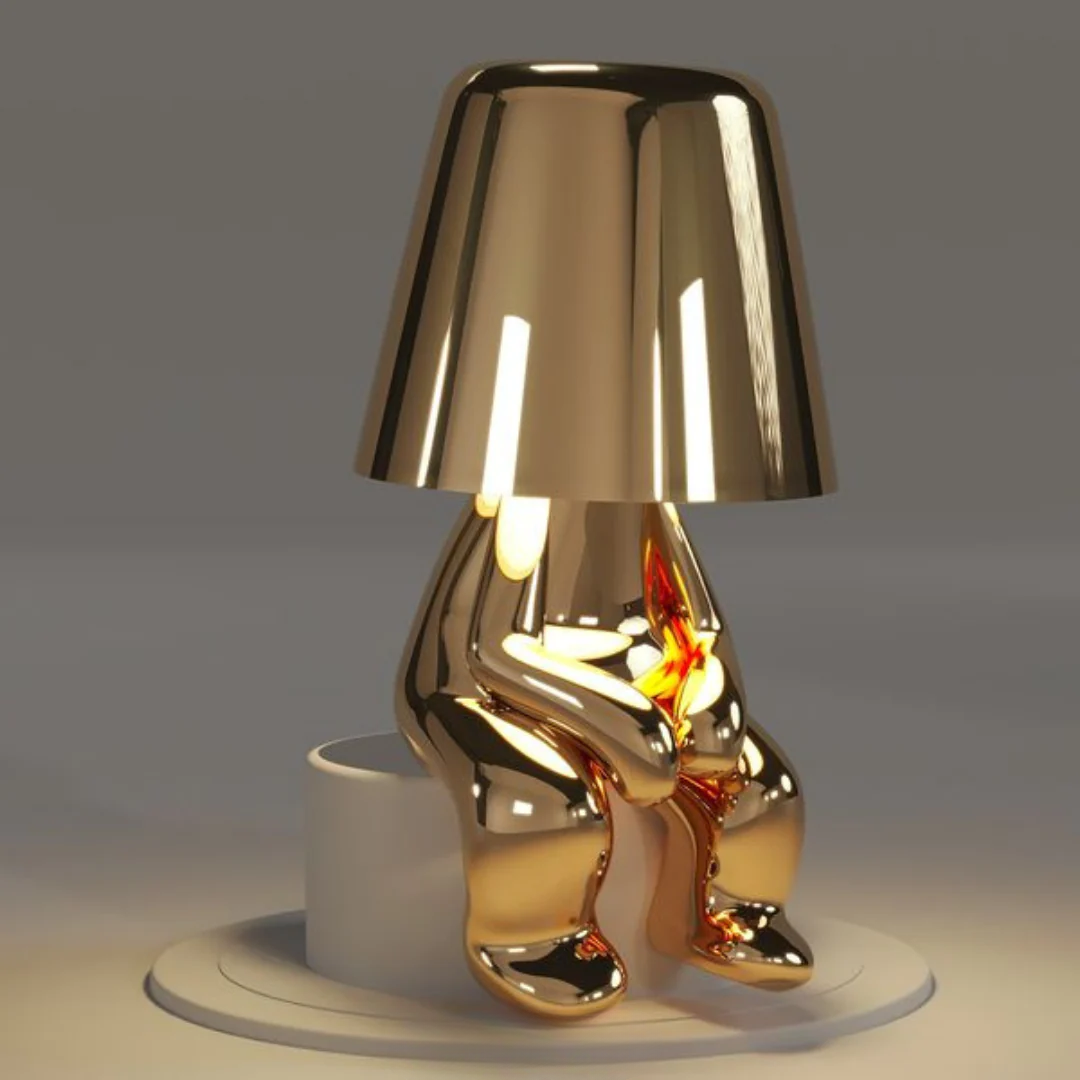 Gold figurine table lamp with conical shade and reflective character base, LED-lit