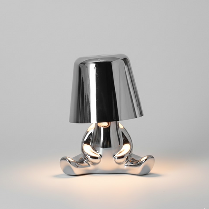 Silver metallic figure table lamp with bell shade and warm glow from inside