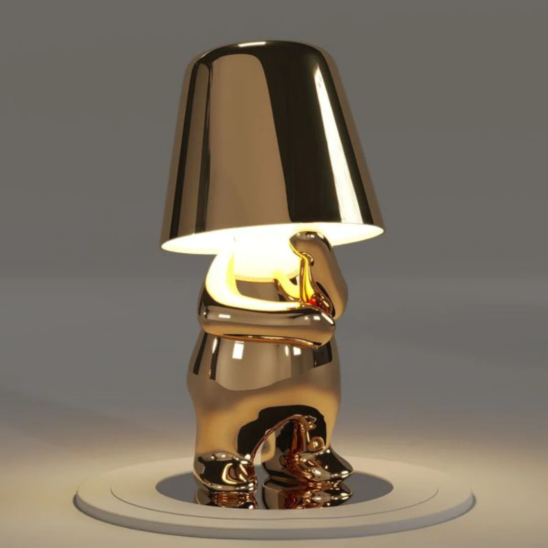 Gold metallic figurine table lamp with glowing conical shade, sculpted body and round base