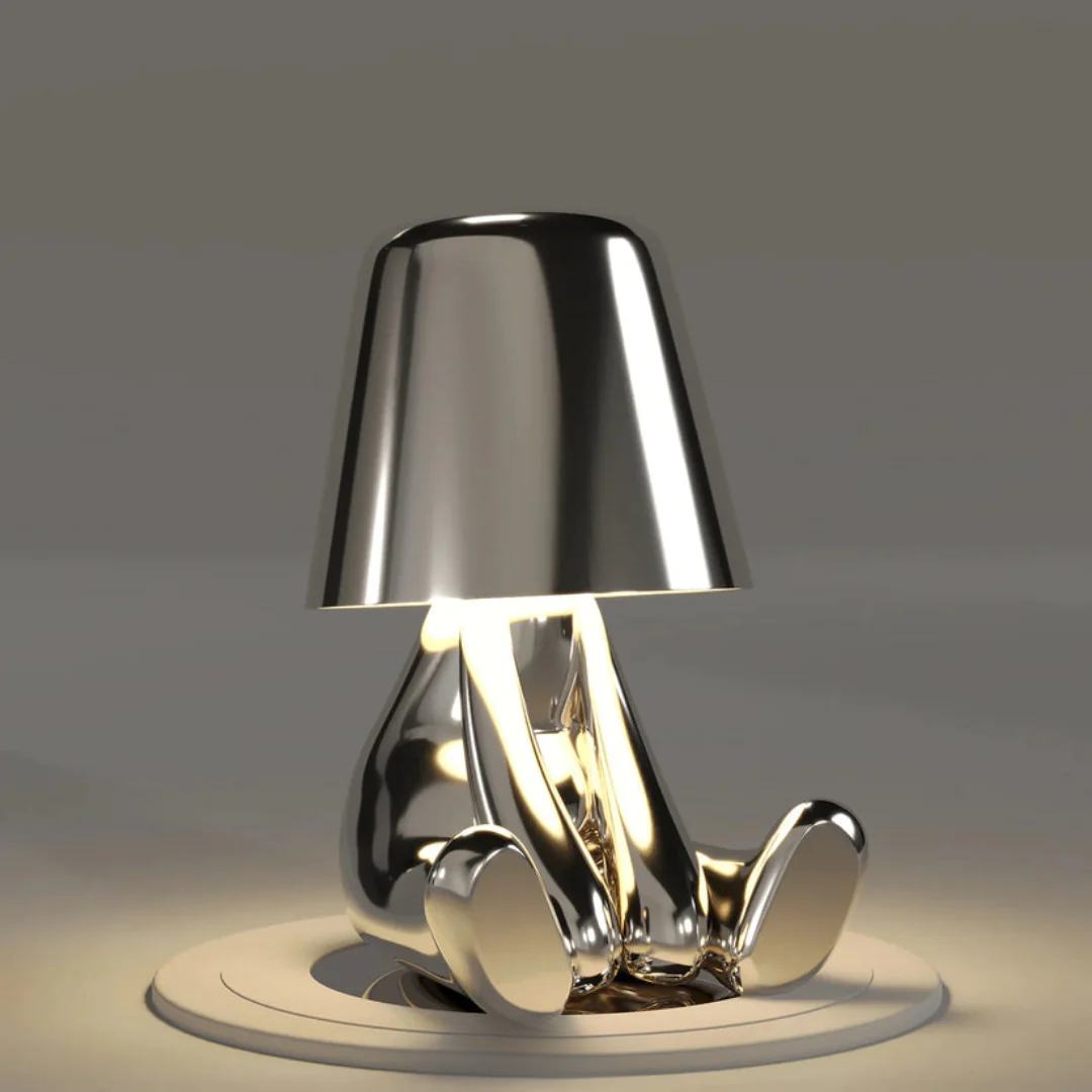 Silver metallic figurine table lamp with conical shade, sculpted base, LED light glow
