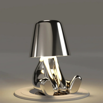 Silver metallic figurine table lamp with conical shade, sculpted base, LED light glow