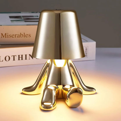 Gold figure table lamp with dome shade and shiny sculpted feet on base