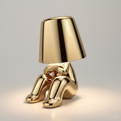 Gold figure table lamp with dome shade and glossy seated pose with legs out