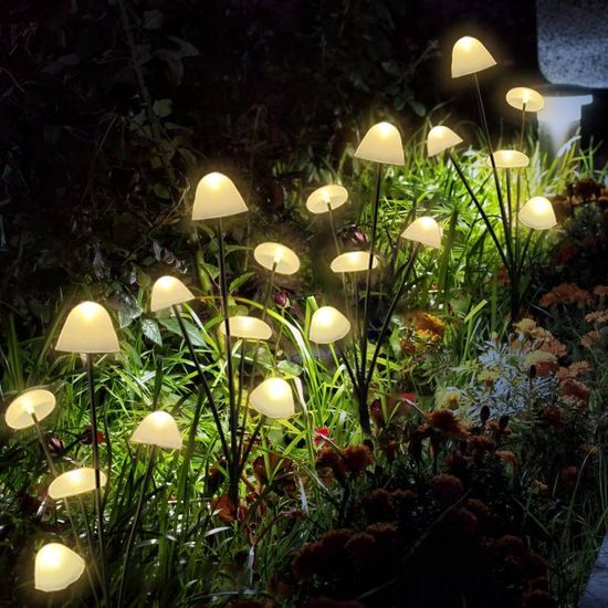 Solar mushroom garden lights glowing among outdoor plants on black stakes
