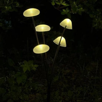 Solar mushroom garden lights glowing in the dark with tall black stakes