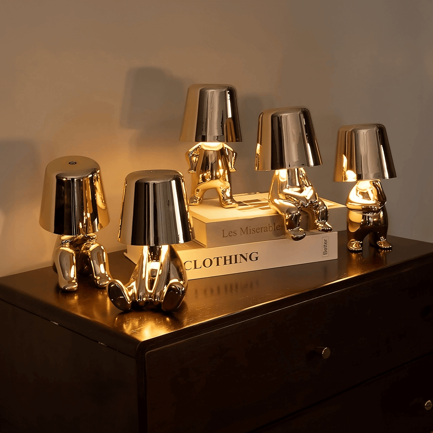 Gold LED figurine table lamps with metallic cone shades, arranged on wooden sideboard