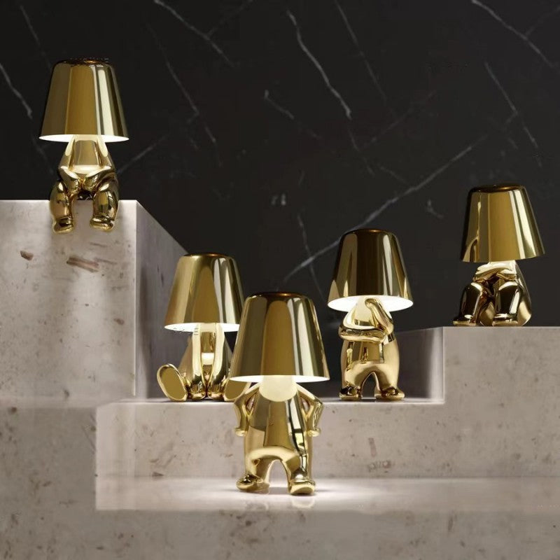 Set of gold figurine table lamps with conical shades on marble surface, LED-lit
