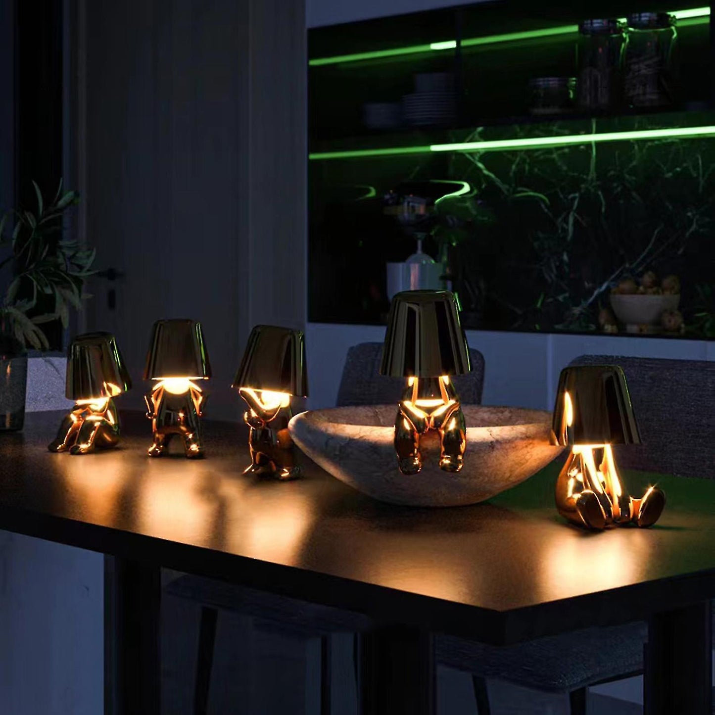 Gold LED figurine table lamps with metallic cone shades, glowing in living area