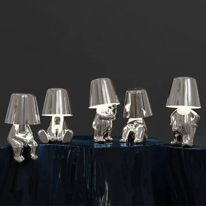 Silver LED figurine table lamps with metallic cone shades on dark table surface