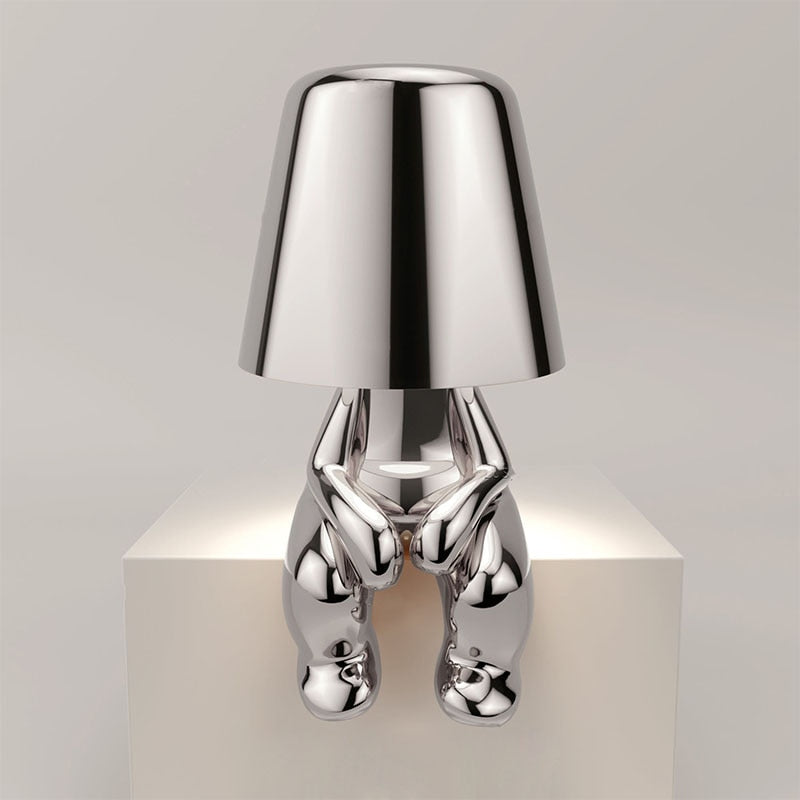 Silver metallic figure table lamp with chrome shade and sculpted humanoid base
