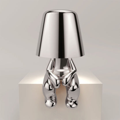 Silver metallic figure table lamp with chrome shade and sculpted humanoid base
