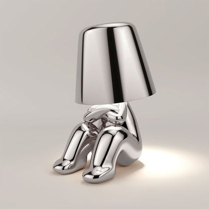 Silver metallic figure table lamp with reflective shade and humanoid sculpted base