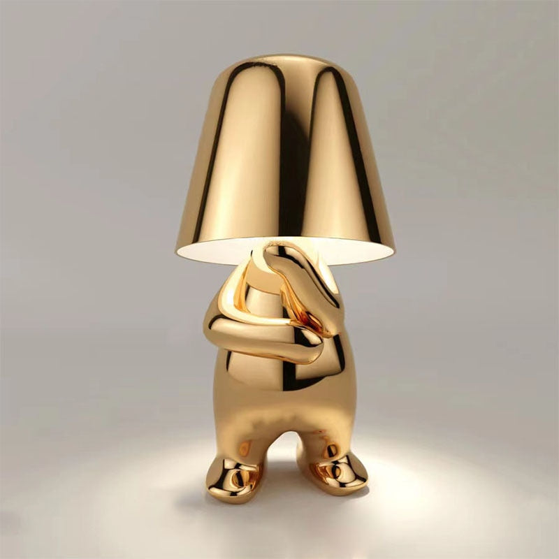 Gold figure table lamp with dome shade and cross-armed sculpted legs