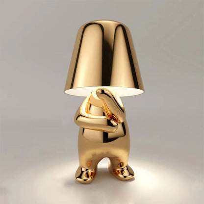 Gold figure table lamp with dome shade and cross-armed sculpted legs