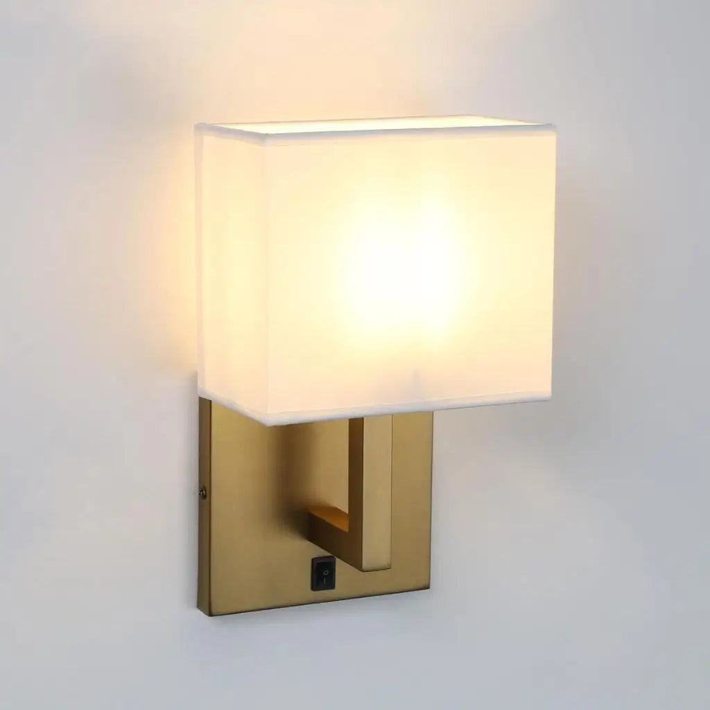 Wall light with white fabric shade and antique gold backplate, angled view