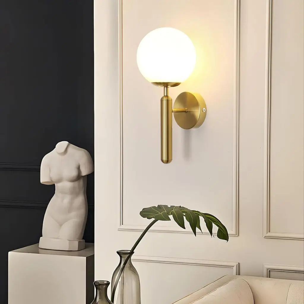 Gold wall sconce with milky glass globe shade and round wall backplate