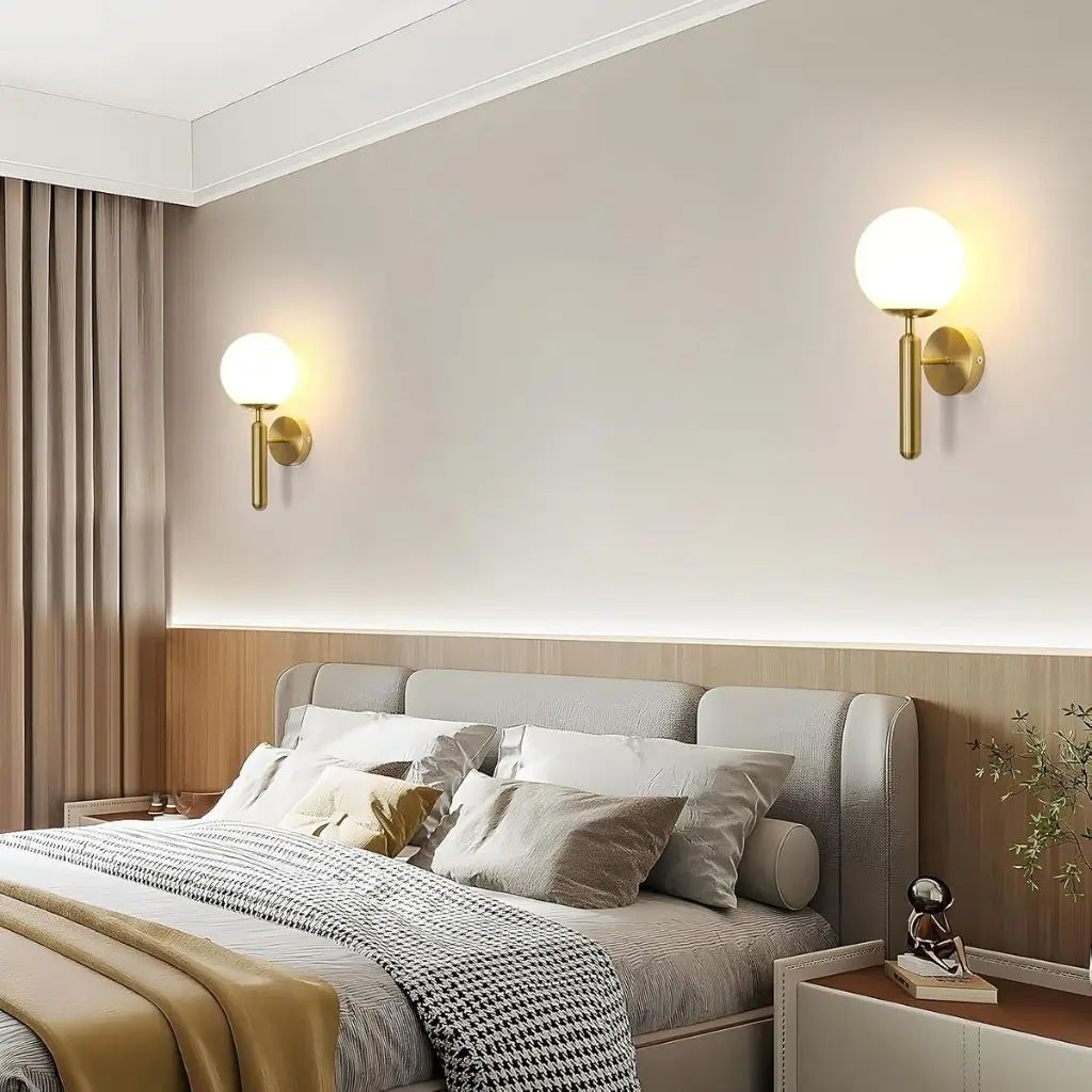 Gold wall sconce pair with milky glass globe shades mounted on the wall