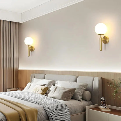 Gold wall sconce pair with milky glass globe shades mounted on the wall