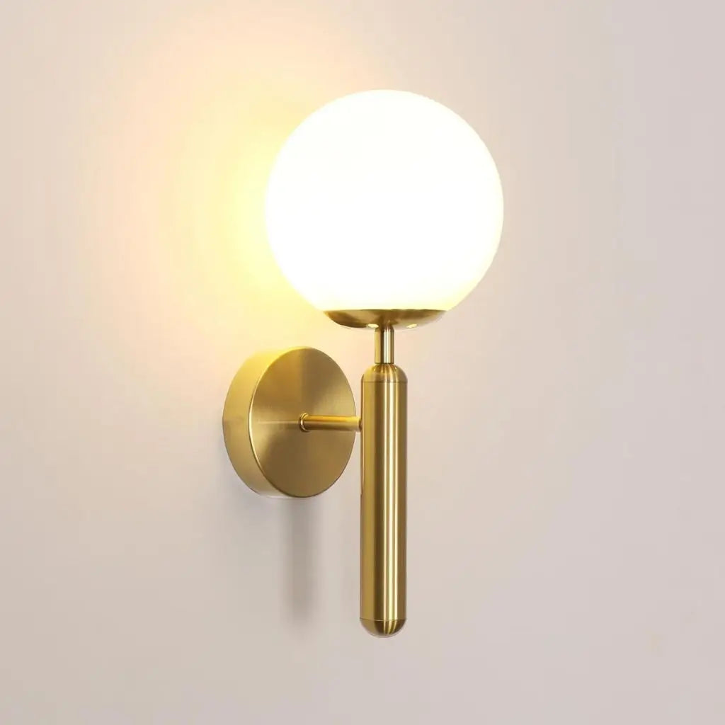 Gold wall sconce with milky glass globe shade and curved round wall backplate