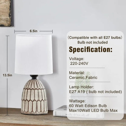 Ceramic table lamp with white fabric shade and patterned gold base, front view