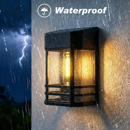 Solar wall lantern light, black frame with warm white glowing bulb behind glass