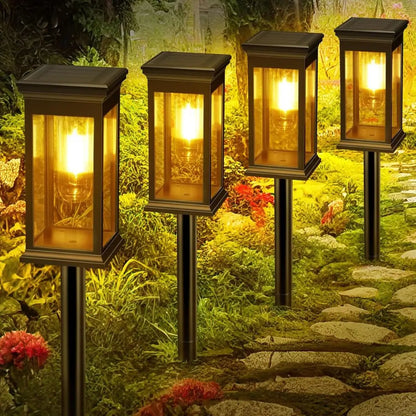 Multiple black solar lantern lights with warm white glow among garden plants