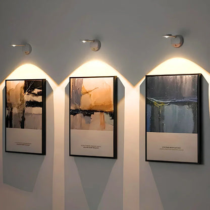 Wireless motion sensor LED wall light trio with warm halo glow behind frames