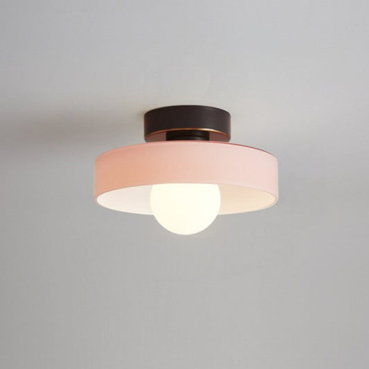 Ceiling light with round pink glass shade and dark metal top, glowing bulb visible