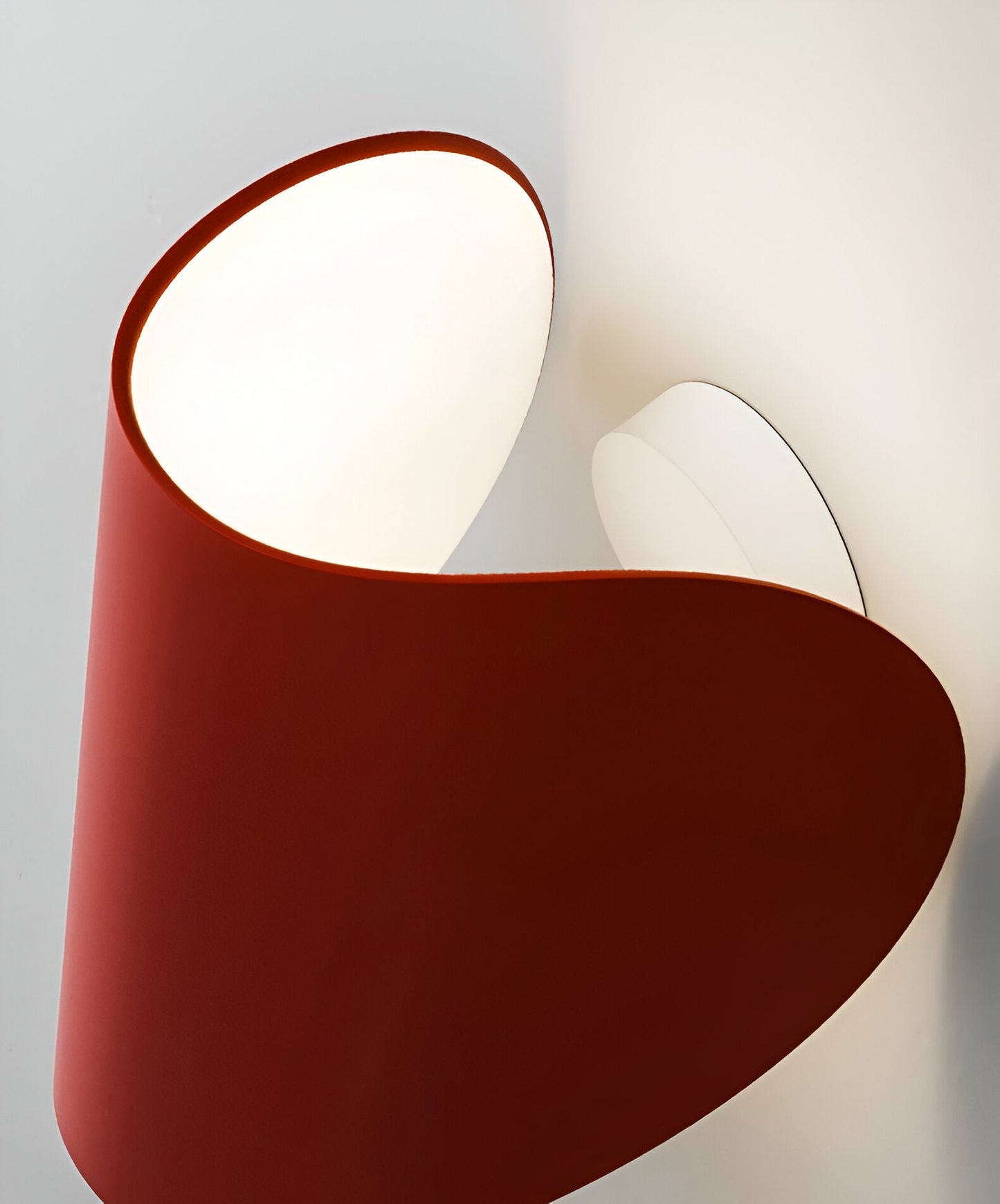 Adjustable metal wall light with red backplate and white interior, angled warm glow.