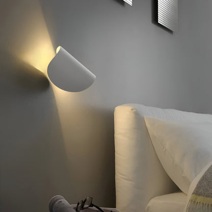 Adjustable metal wall light with light-gray cone shade, angled for focused warm illumination.
