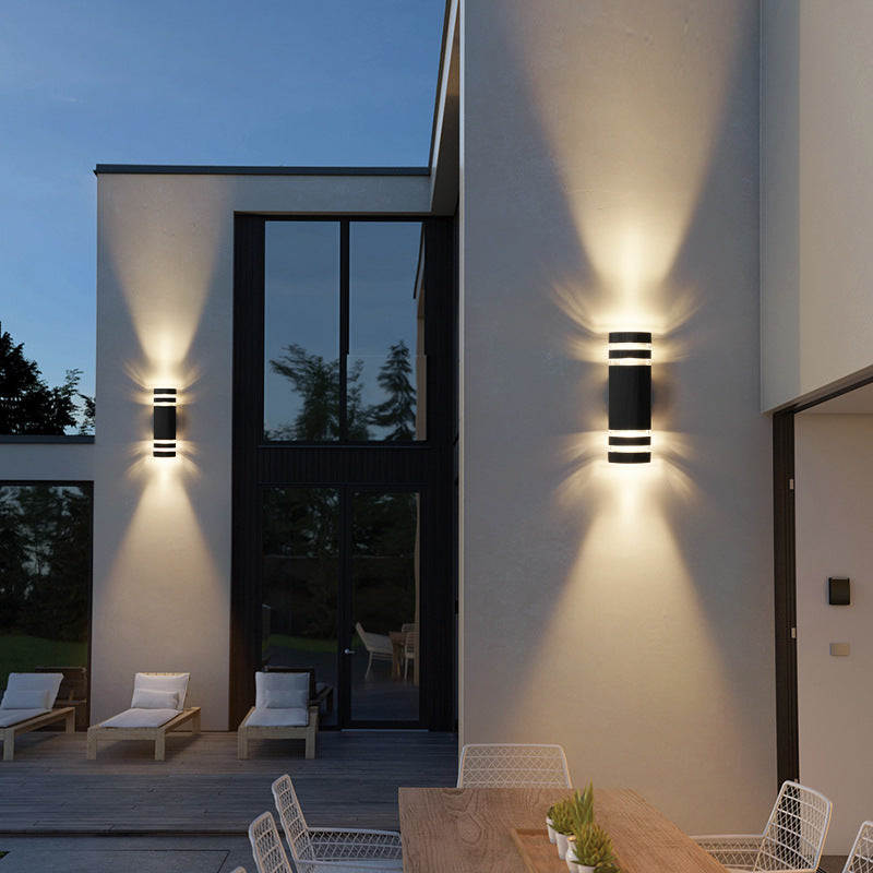 Outdoor wall light with aluminum trim and dark glass, wall-mounted, emitting warm light