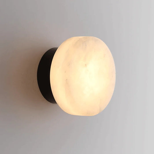 Black LED wall light with round marble-effect diffuser, emitting warm glow