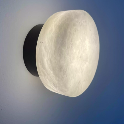 Black LED wall sconce with large oval marble-effect diffuser, warm white glow