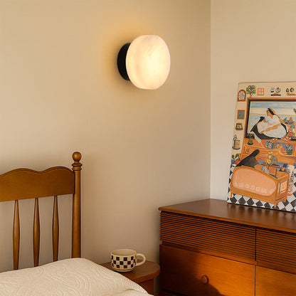 Black round LED wall light with marble-effect glass shade, warm indoor lighting