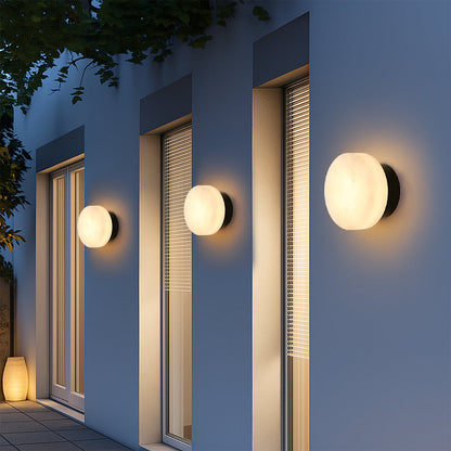 Outdoor black LED wall light with round marble-effect diffuser, warm light at night