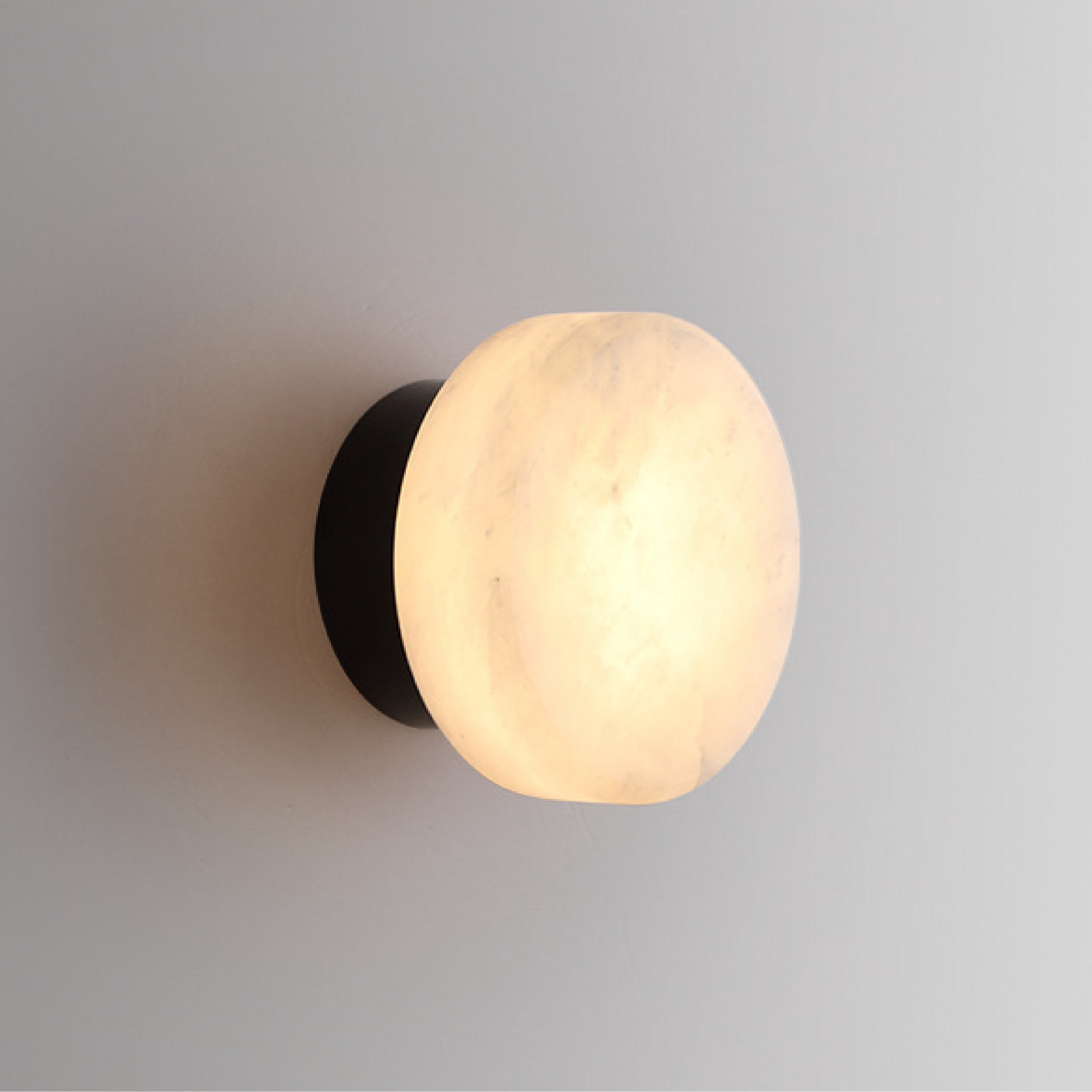 Black LED wall light with round marble-effect diffuser, warm illumination
