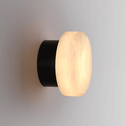 Black-and-marble-effect LED wall sconce with round diffuser emitting warm light