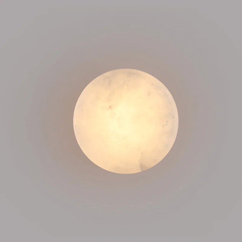 Round marble-effect LED wall light with soft warm glow on smooth surface