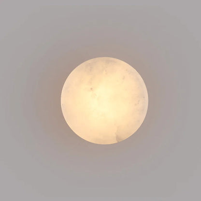 Round marble-effect LED wall light with soft warm glow on smooth surface