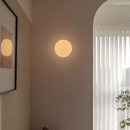 Round glass wall light with warm glowing globe on wall