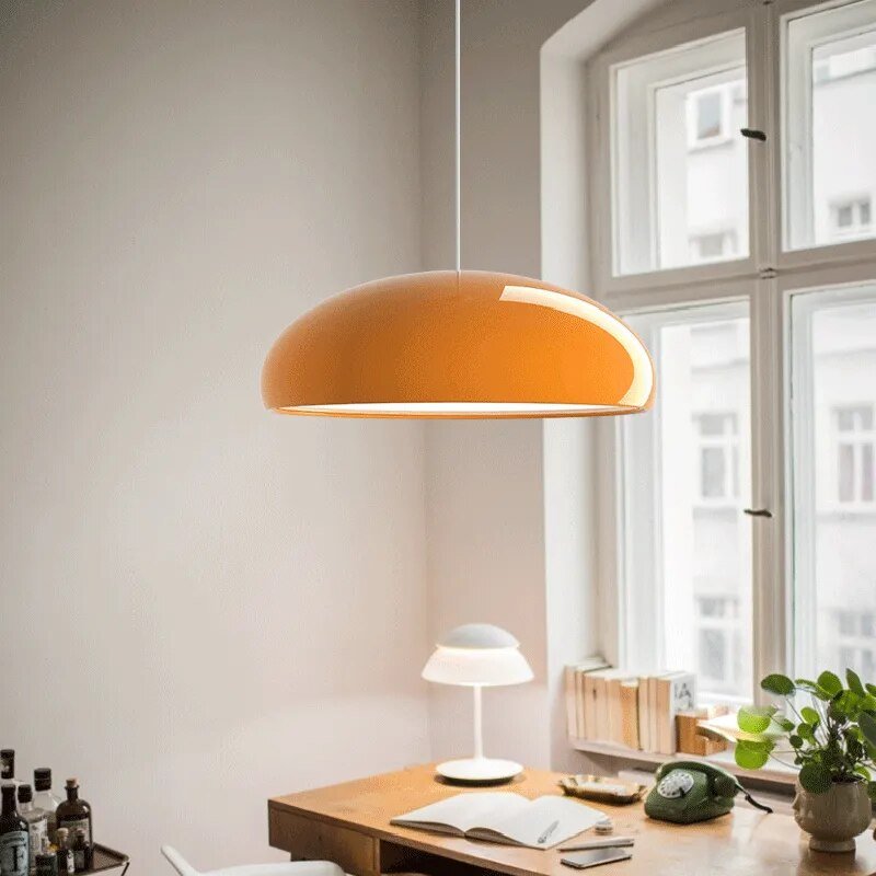 Modern metal and acrylic pendant light with orange dome shade on a cord