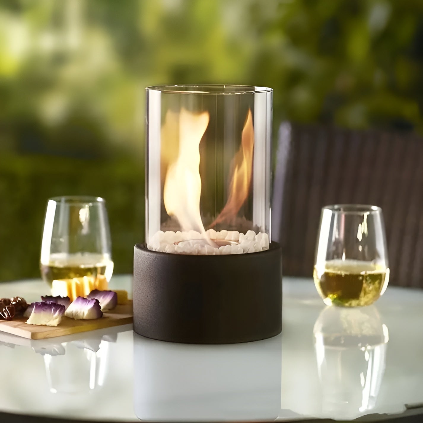 Tabletop bioethanol fireplace with clear glass fire bowl and dark metal base, flames inside