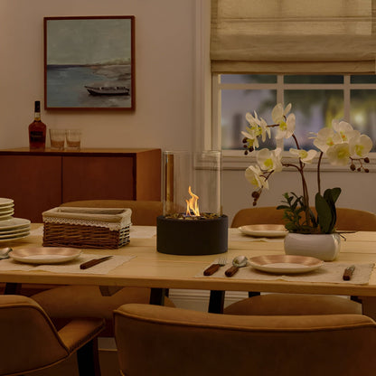 Tabletop bioethanol fireplace with clear glass fire bowl and black metal base, flame visible