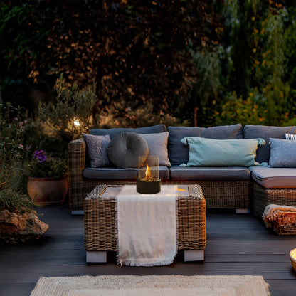 Tabletop bioethanol fireplace with clear glass fire bowl and black metal base, flames on terrace