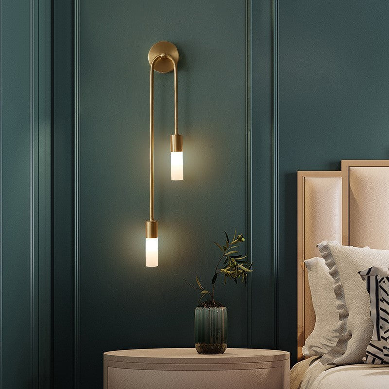Gold LED wall sconce with curved backplate and two vertical warm white cylinder lights