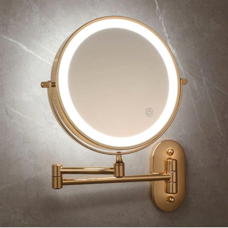 Wall-mounted round cosmetic mirror with gold frame, LED ring, and swivel wall mount