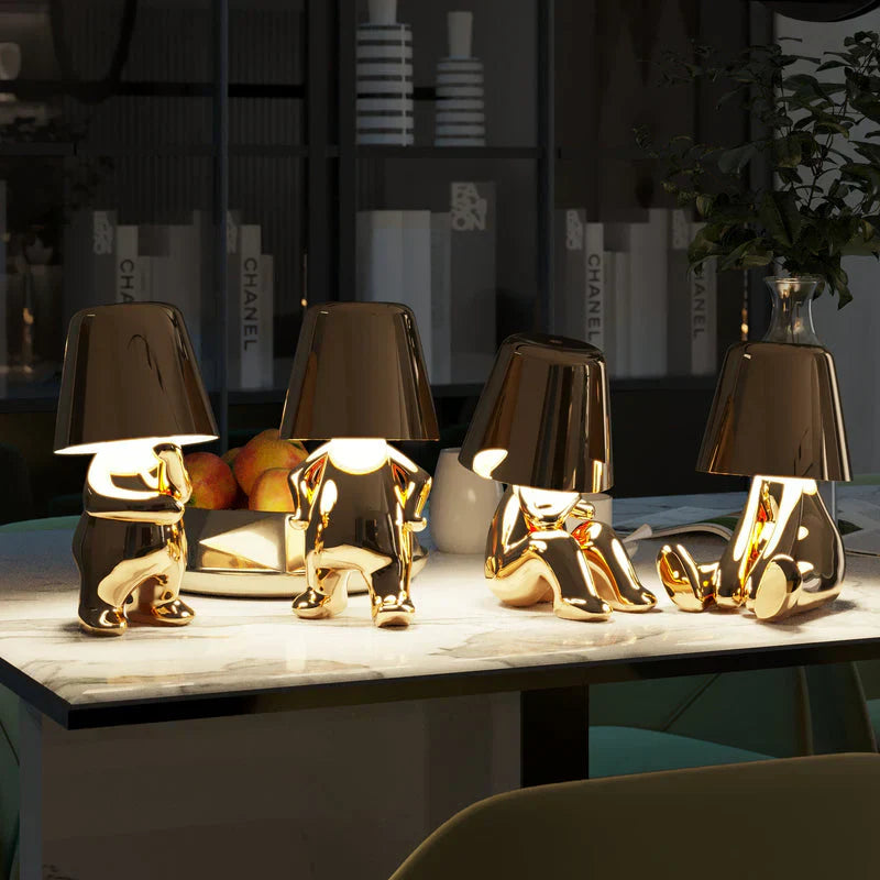 Gold LED figurine table lamps with metallic cone shades, glowing on countertop