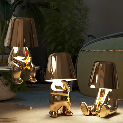 Gold LED figurine table lamps with metallic cone shades, lit warm glow